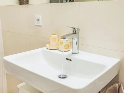 a bathroom sink with a faucet and two cups on it at Apartment Washington-2 by Interhome in Prague