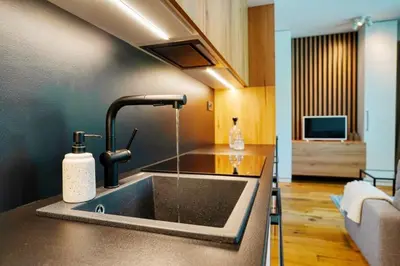 a kitchen with a sink and a living room at Carme Apartment with Parking in Prague