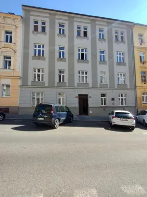 two cars parked in front of a large building at Two bedroom apartment with parking in Prague