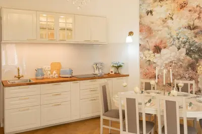 a kitchen with white cabinets and a table with chairs at Tynska apartment in Prague