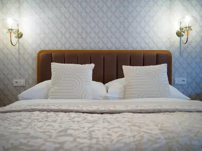 a bed with white pillows and a wooden headboard at Hotel 16 & Apartments Prague City Living in Prague
