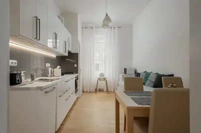 a kitchen with white cabinets and a table with a counter top at Sweet Spot for 6 in Trendy Area! Family friendly! in Prague