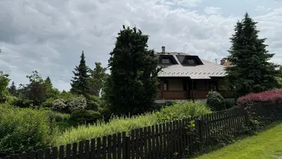 a house behind a fence with trees and bushes at Křivoklátské Johnyho bydlení in Křivoklát