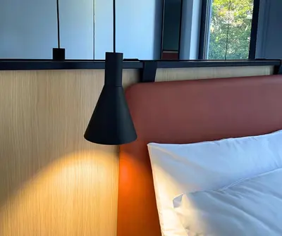 a black lamp next to a bed in a room at WE Hotel EXPO Prague in Prague