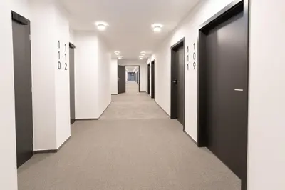 a corridor of corridors in an office building with black doors at WE Hotel EXPO Prague in Prague