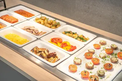 a counter with trays of different types of food at WE Hotel EXPO Prague in Prague