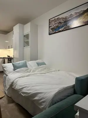 a bedroom with a white bed with a painting on the wall at Cozy Modern Apartment, 20 mins to Center in Prague