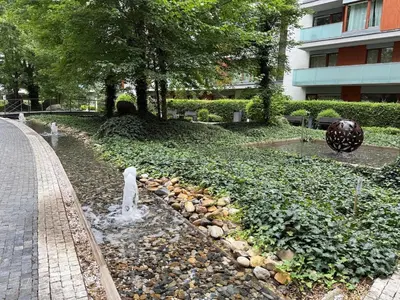 a fountain in the middle of a park with a building at Karlín Diamond View & Garage in Prague
