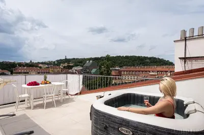a woman sitting in a hot tub on a balcony at Blue Sky Residence in Prague