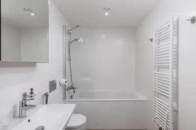 a white bathroom with a tub and a sink at Elegant Prague Flat with Balcony, Workspace, Garage in Prague