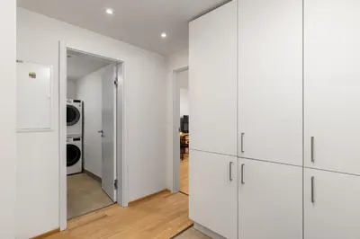 a laundry room with white cabinets and a washer and dryer at Elegant Prague Flat with Balcony, Workspace, Garage in Prague