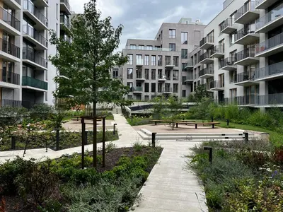 a park with benches and a tree and buildings at Elegant Prague Flat with Balcony, Workspace, Garage in Prague
