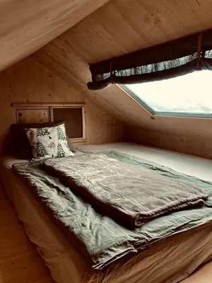 a bed in a wooden cabin with a window at Escape to the Czech Republic in this Wonderful Tree House in Nature in Prague