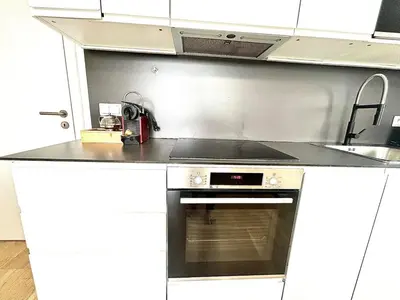 a white kitchen with white cabinets and a wooden floor at Bright Apartment - Na Vinici Prague 2 in Prague
