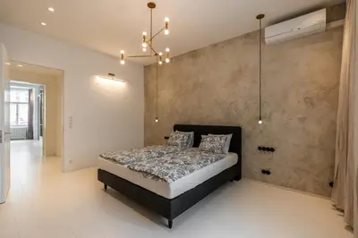 a bedroom with a bed and a concrete wall at Luxury Old Town Penthouse w park in Prague