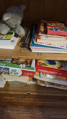 a stack of books on a wooden table with a teddy bear at Apartmán ANNA