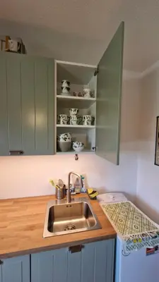 a kitchen with a sink and green cabinets at Apartmán ANNA