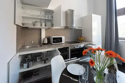 a kitchen with white cabinets and a table with orange flowers at Loft cozy studios in Prague Center in Prague