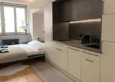 a kitchen with white cabinets and a bed in a room at Cosy Apartment near City Center in Prague