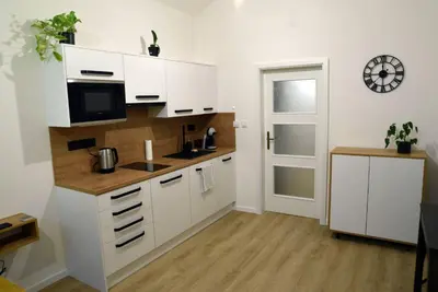 a kitchen with white cabinets and a clock on the wall at The Nook I Soukromý apartmán v srdci Prahy in Prague