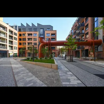 a large red pipe in a city with buildings at Apartman made by David Černý in Prague
