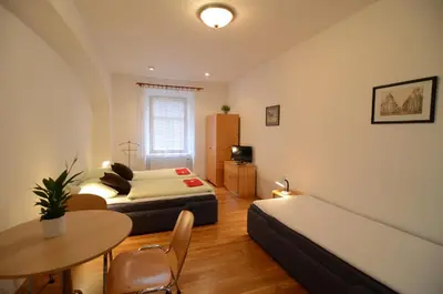 a small room with two beds and a table and a tableablish at Apartments Karlin in Prague