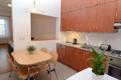 a kitchen with wooden cabinets and a table with chairs at Apartments Karlin in Prague
