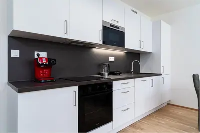 a kitchen with white cabinets and a red appliance at Bright Royal Elegance in Prague