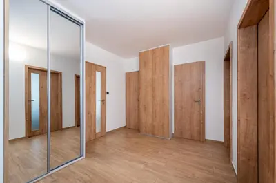 an empty room with wooden doors and a mirror at Luxury modern apartment near the metro - 10 minutes to the city center in Prague