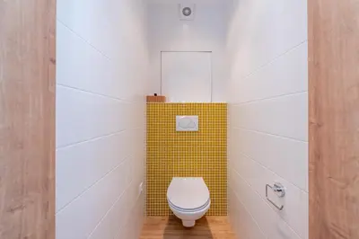 a bathroom with a toilet with a yellow tile at Luxury modern apartment near the metro - 10 minutes to the city center in Prague