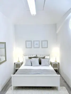 a white bedroom with a white bed and two night stands at Elegant Cozy Apartment In center Prague in Prague