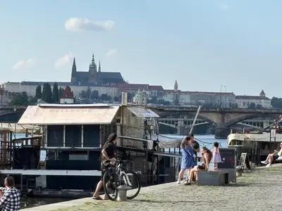 a group of people sitting on a dock with a boat at Riverside apartment in Prague