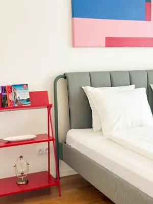 a bed with a red nightstand next to a red table at New Modern Apartment in Center with Terrace and Parking in Prague