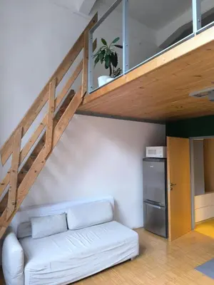 a living room with a white couch under a staircase at Loft Palmovka in Prague