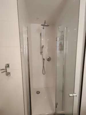 a white bathroom with a shower with a glass door at Free Parking Modern Smíchov Apartment With Large Balcony in Prague