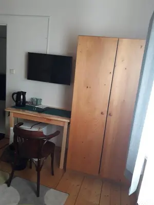 a desk with a television and a wooden cabinet at Penzion Na Střelnici in Poděbrady