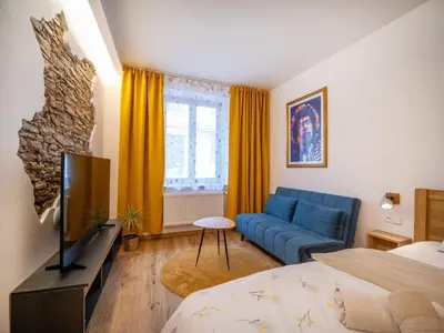 a living room with a blue couch and a bed at Apartmán Jimi Hendrix in Nymburk