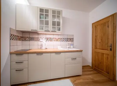 a kitchen with white cabinets and a wooden door at Apartmán Jimi Hendrix in Nymburk