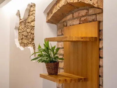 a plant on a wooden shelf next to a stone wall at Apartmán Jimi Hendrix in Nymburk
