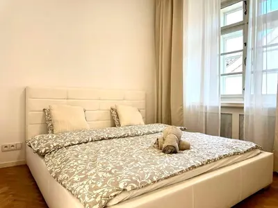 a white bed with a stuffed animal on top of it at Awesome Apartment Charles Bridge in Prague