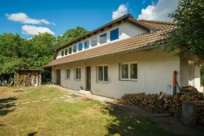 a house being constructed with a pile of wood at Strom času