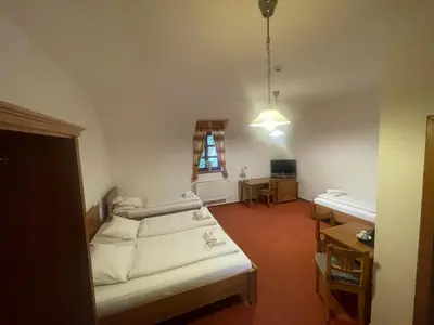 a room with two beds and a desk and a window at Restaurace a Penzion U Labutě in Prague