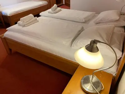two beds with white sheets and a lamp on a table at Restaurace a Penzion U Labutě in Prague