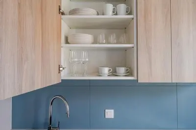 a kitchen cabinet with plates and glasses and a sink at Blueground Nusle city view nr Vysehrad PRG-69 in Prague