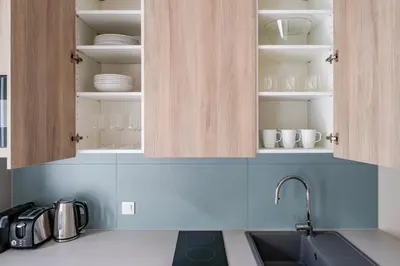 a kitchen with a sink and cabinets with dishes at Blueground Nusle balcony nr Vysehrad PRG-72 in Prague