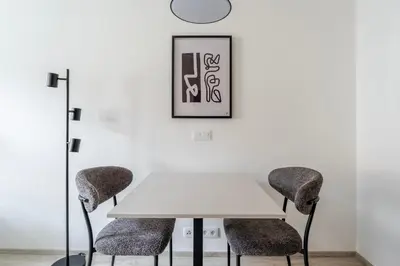 a white table with two chairs and a clock on the wall at Blueground Nusle balcony nr Vysehrad PRG-64 in Prague