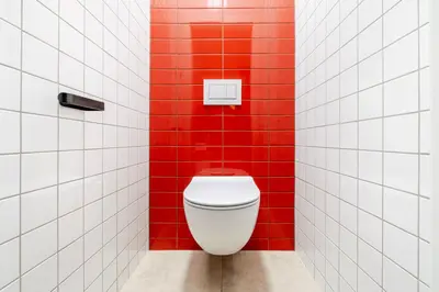 a bathroom with a white toilet in a red wall at Blueground Vinohrady balcony nr Riegrovy Sady PRG-78 in Prague
