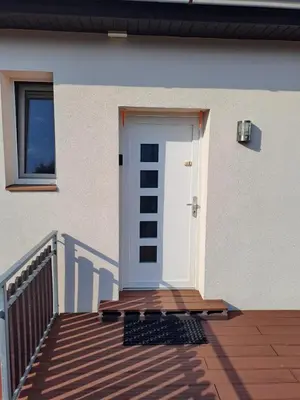 a white door on a house with a wooden deck at H apartment in Jankov