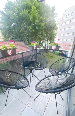 three chairs and a table on a balcony with flowers at New Apartment Prague 5 in Prague
