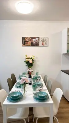 a white dining room table with blue plates and flowers at New Apartment Prague 5 in Prague